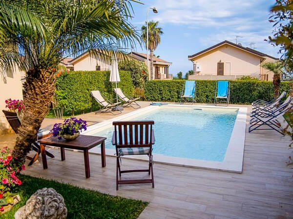 Pool mit Palmen und Sonnenliegen