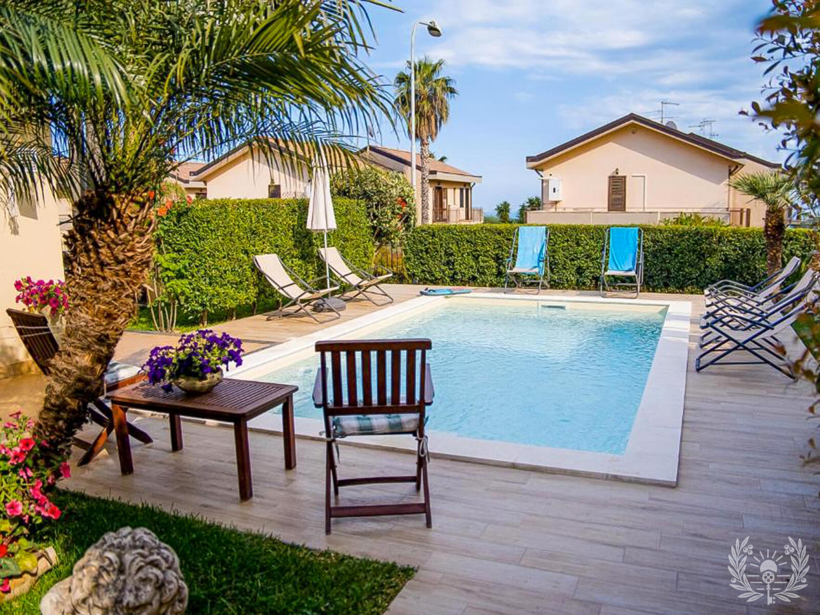 Pool mit Palmen und Sonnenliegen